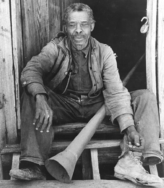 Бывший раб держит рог, который был использован плантаторами для..0