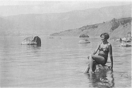 Комсомолка в прозрачном купальнике позирует на фоне моря в..0
