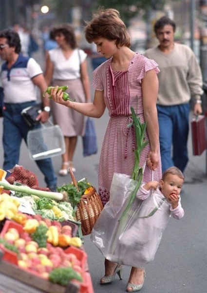 Мать держит свою дочь в сумке во время шоппинга на рынке..0