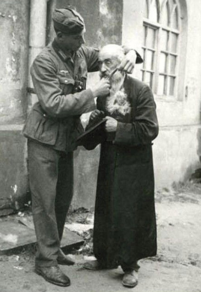 Молодой немецкий солдат унижает пожилого еврея, обрезая ему..0