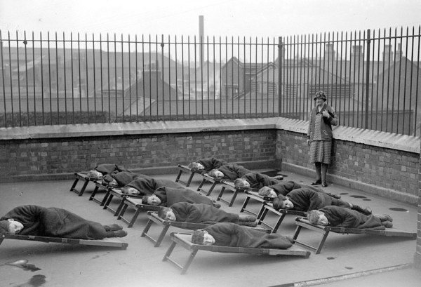 Дети спят на деревянных кроватях под брезентовыми покрытиями..0