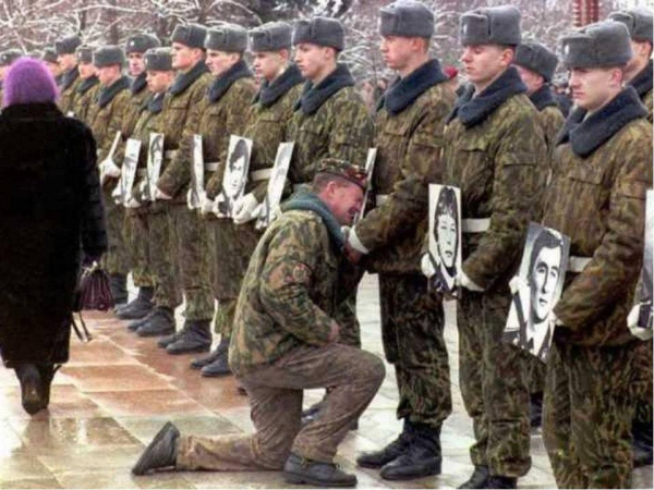 Ветеран Афганской войны плачет, стоя на колене у портрета своего..0